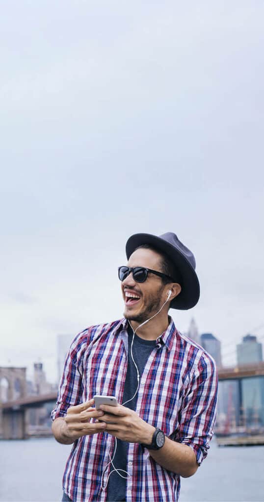 man smiling while wearing headphones, sunglasses and hat